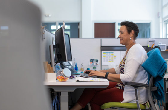 Grow team member sits wearing a headset, working on a computer