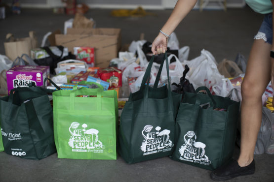 Grow Financial Foundation board member stands next to food donations that will help fight food insecurity