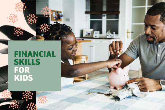 Young girl at table with green checked tablecloth with her father adding coins to save in her pink piggy bank with headline "Financial Skills for Kids" overlaid.
