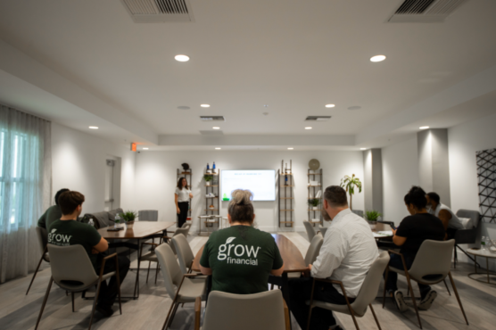 A professional training session at Grow Financial, with an individual presenting to participants seated around tables.